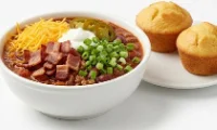 Berts-Best-Bowl-of-Chili-with-Sides Loaded bowl of chili with bacon, jalapeños, and cheese served with cornbread.