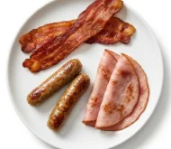 Breakfast-Meat-Sides-Platter-White-Background Breakfast meat platter with crispy bacon, grilled sausage links, and sliced city ham.