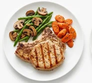 Grilled-Pork-Chop-Dinner-with-Vegetables A grilled pork chop with sautéed mushrooms, green beans, and carrots.