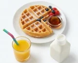 Kids-Waffle-Breakfast-Meal-with-Drinks Kid-sized waffle with berries and syrup served with orange juice and milk.