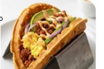 The Waffle Taco A breakfast creation featuring scrambled eggs, chorizo, and avocado nestled inside a crispy, folded waffle shell.